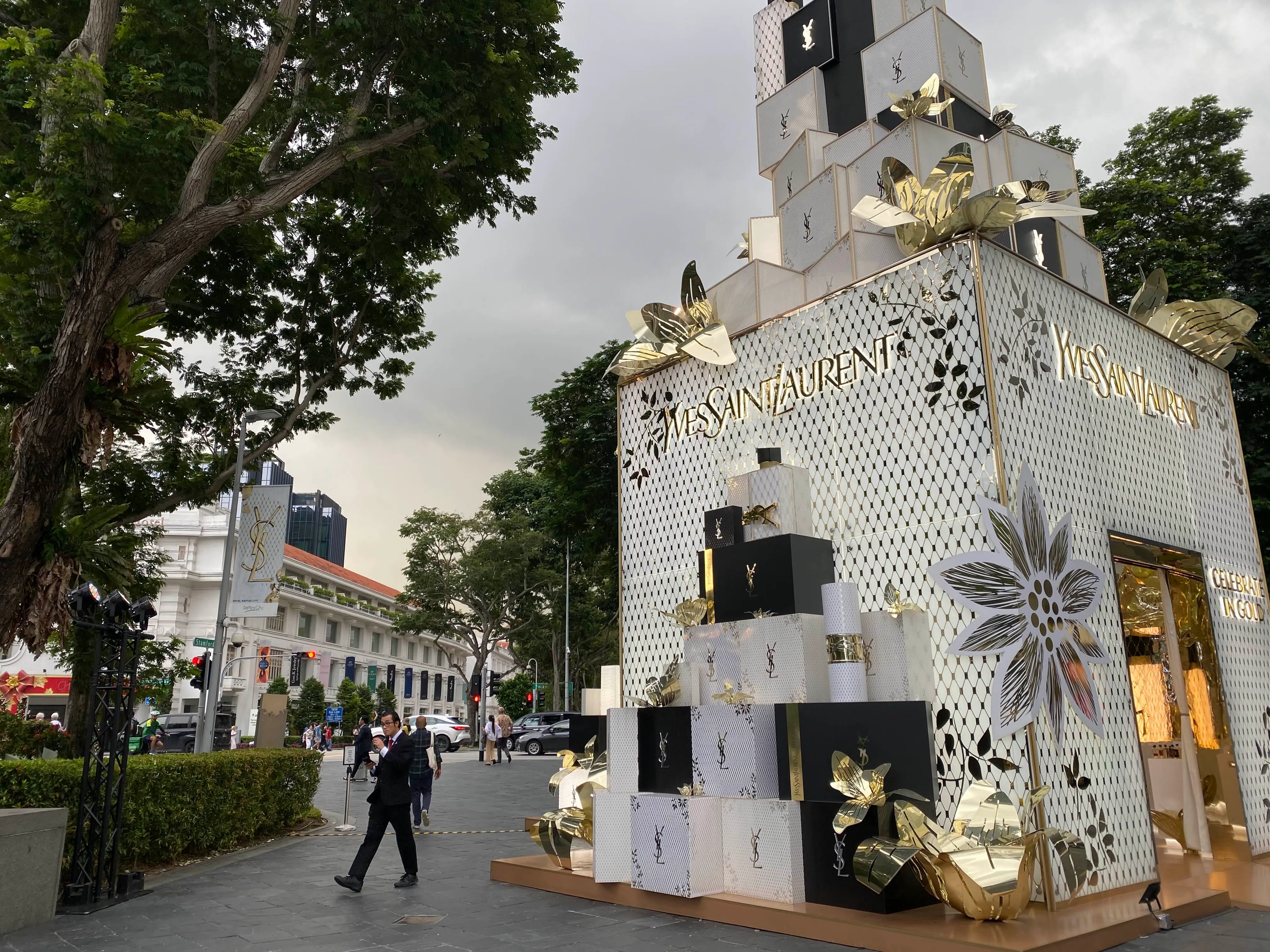 A large Yves Saint Laurent white gift box is displayed as an outdoor installation outside Raffles City near the traffic light crossing.