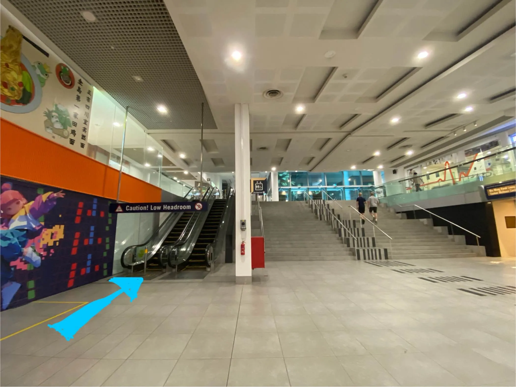 Underpass in the basement of SMU. There are escalators and stairs heading up.